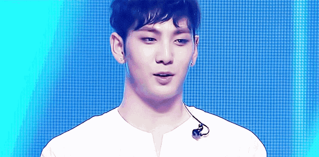 a young man wearing a white shirt and earphones looks at the camera