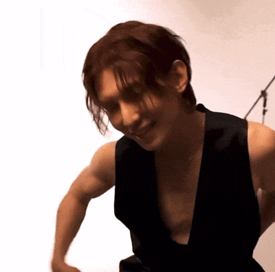 a man wearing a black vest is smiling and looking down at something
