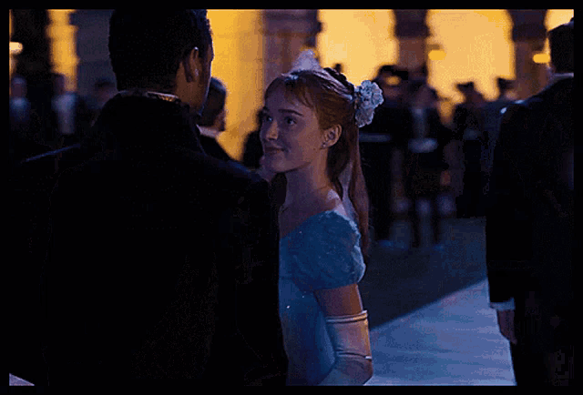 a woman in a blue dress is standing next to a man in a suit