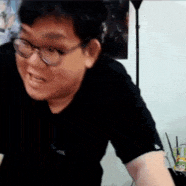a man wearing glasses and a black shirt is making a funny face in a room .