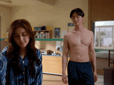 a man without a shirt is standing next to a woman in a bedroom