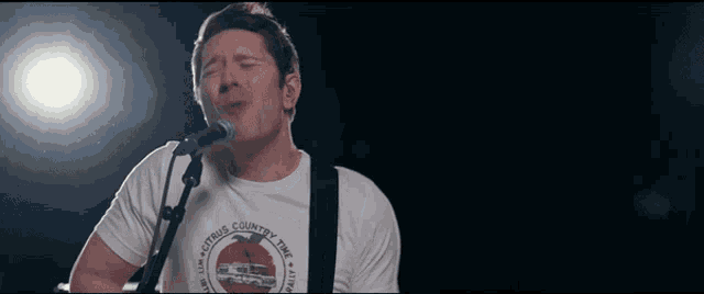 a man is singing into a microphone wearing a shirt that says citrus country time