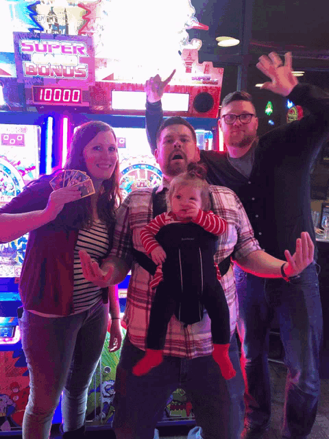 a group of people are posing for a picture in front of a super bonus machine