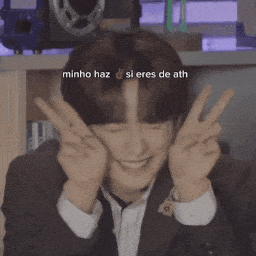 a young man in a suit and tie making a peace sign with the words minho haz si eres de ath below him