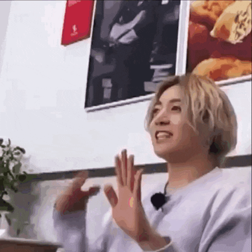 a young man is sitting at a table with his hands in the air and making a funny face .