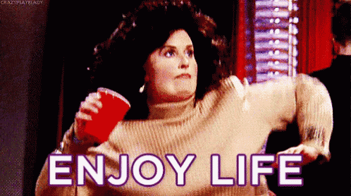 a woman in a sweater is holding a red cup with the words enjoy life written on it .