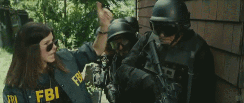 a woman wearing a fbi shirt is standing in front of a building