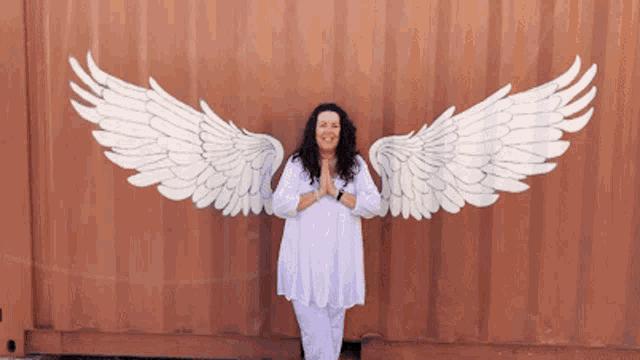 a woman standing in front of a wall with wings painted on it