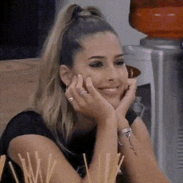 a woman is smiling with her hands on her face