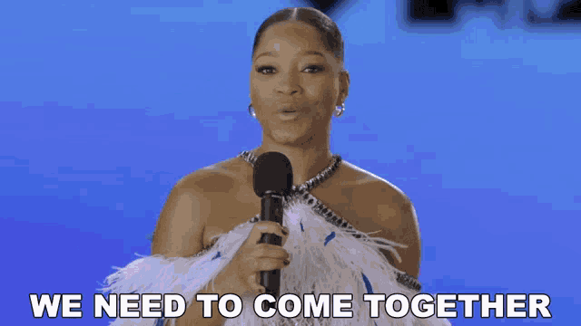 a woman holding a microphone with the words we need to come together behind her