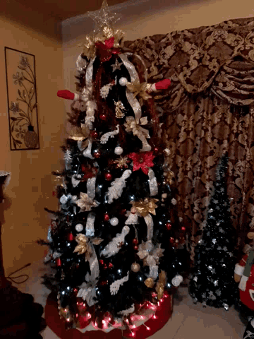 a christmas tree with red white and gold decorations is in a living room