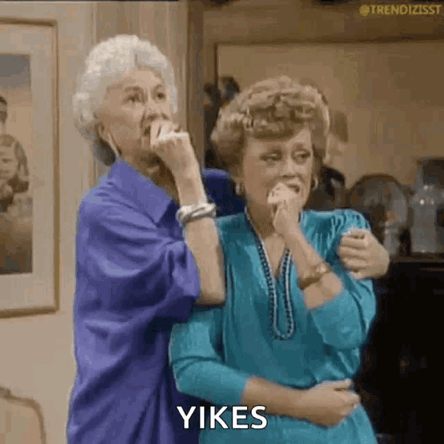 two older women are standing next to each other and one of them is holding the other 's hand .