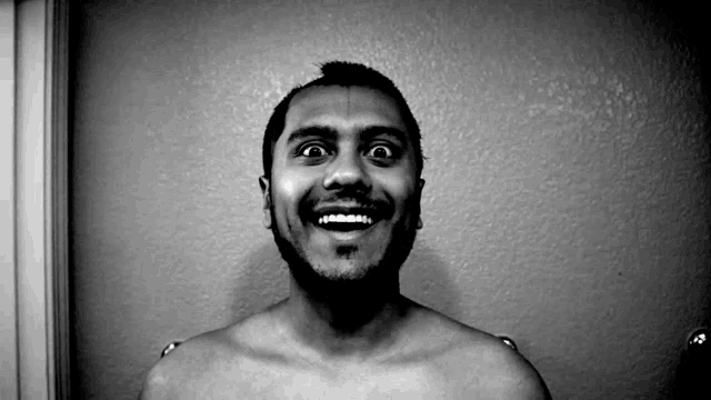 a man without a shirt is smiling and looking up at the camera