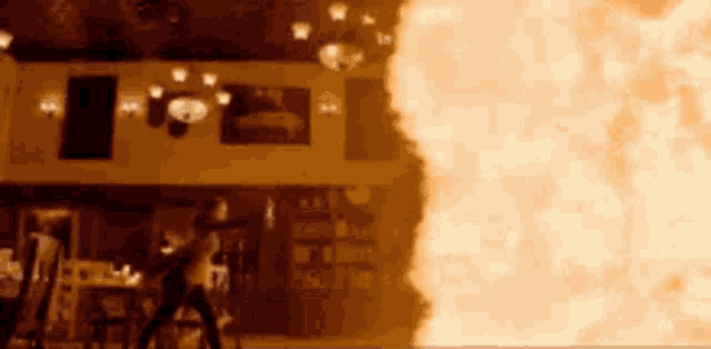 a woman is standing in front of a large fire in a room