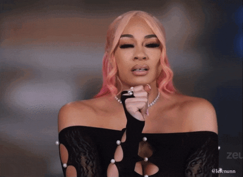 a woman with pink hair is wearing a black top with pearls