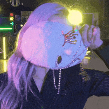 a woman with purple hair is wearing a white mask with rhinestones on it