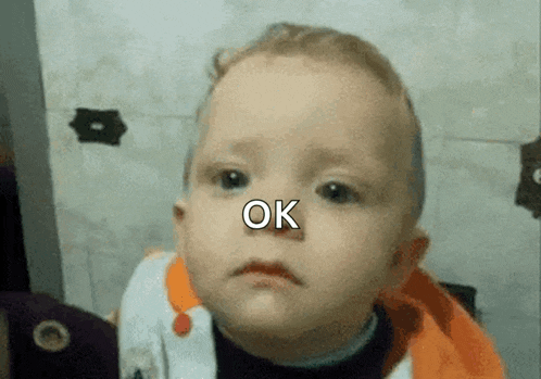 a baby with a sad look on his face has the word ok on his nose