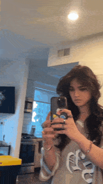 a girl is taking a picture of herself in the mirror with her phone .