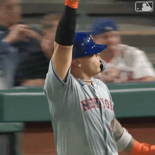 a baseball player wearing a new york mets jersey is holding his arms up in the air .