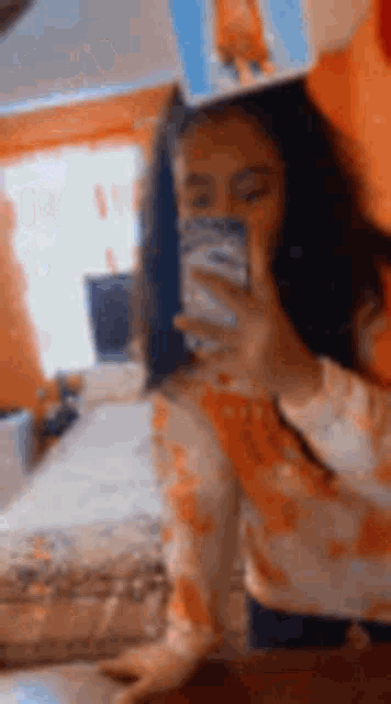a girl is taking a selfie with her cell phone in a room .