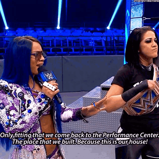 two female wrestlers are talking to each other and one of them is holding a microphone