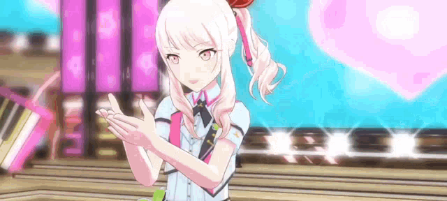 a girl with white hair is standing on a stage with her hands folded in front of a pink heart .