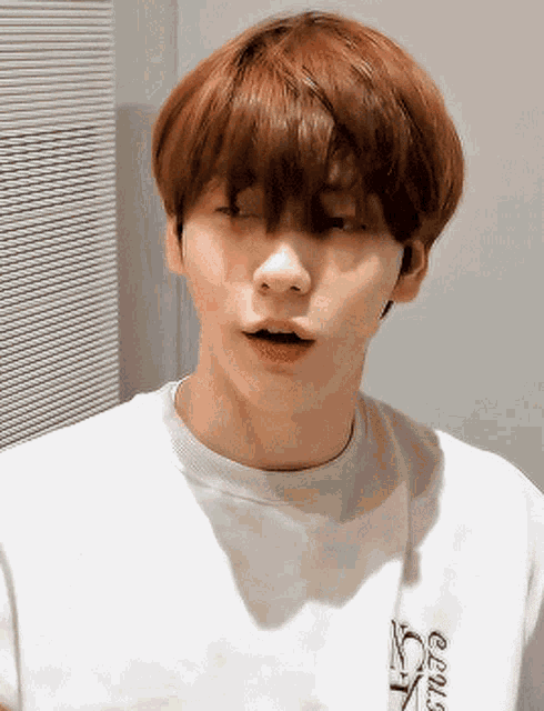 a young man with red hair is wearing a white t-shirt that says gems on the front