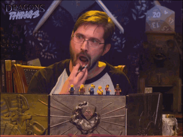 a man sitting at a table with a dragon 's things advertisement behind him
