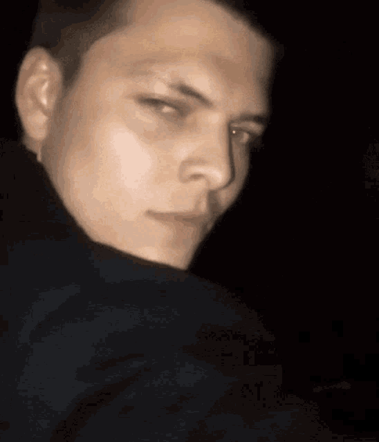 a close up of a young man 's face with a black background