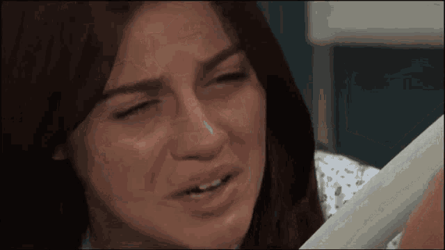 a woman in a hospital gown is crying while holding a paper