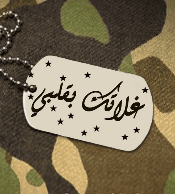 a dog tag with arabic writing on it is on a camouflage background