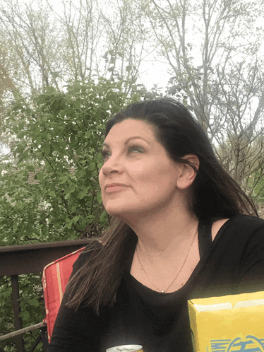 a woman sits on a deck with a can of soda and a box of ea