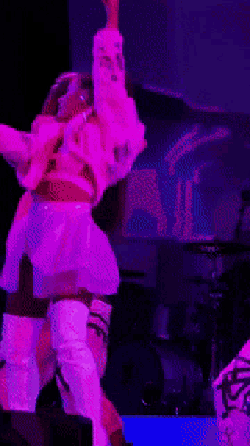 a woman is singing into a microphone on a stage with purple lights behind her
