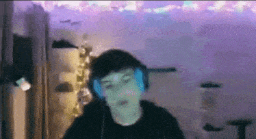 a man wearing headphones is dancing in a room with a christmas tree in the background .