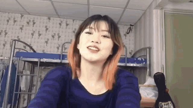 a woman is taking a selfie in front of a bunk bed in a dorm room .