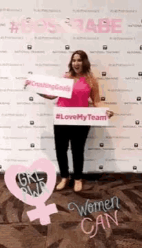 a woman in a pink shirt is holding a sign that says " love my team "
