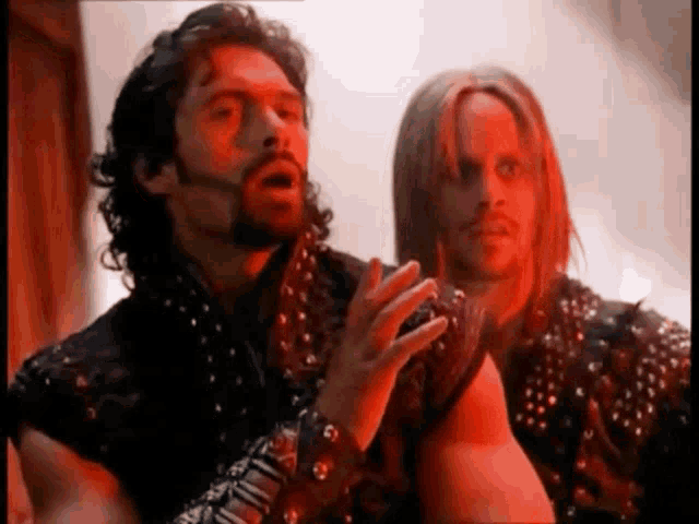 a man with a beard and a woman with long hair are standing next to each other in a dark room .