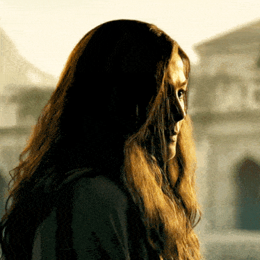 a woman with long brown hair is wearing a black jacket