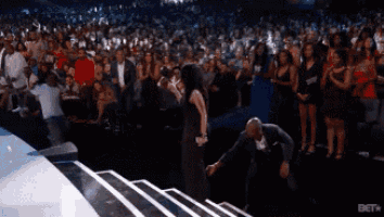 a man and a woman are dancing in front of a crowd at a concert sponsored by bet