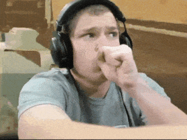 a man wearing headphones and a grey shirt is making a funny face