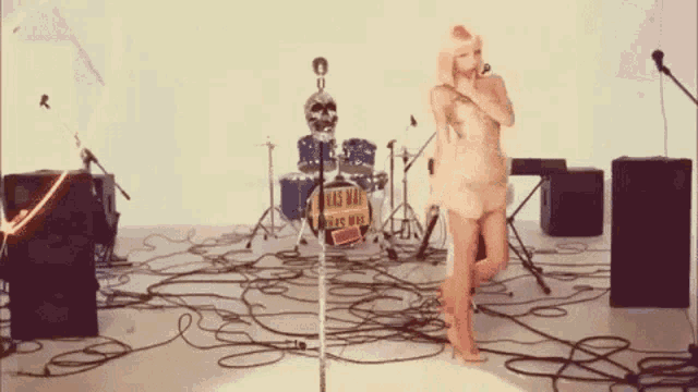 a woman singing in front of a drum set with a sign that says ' kiss man ' on it