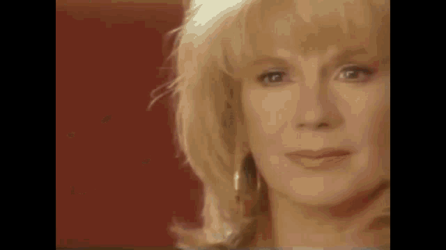 a close up of a woman 's face with blonde hair and a red background
