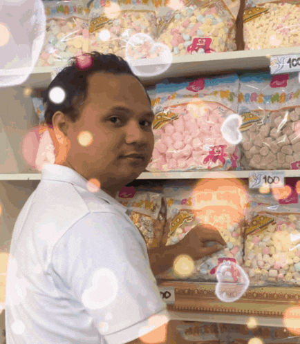 a man is standing in front of a shelf full of marshmallows