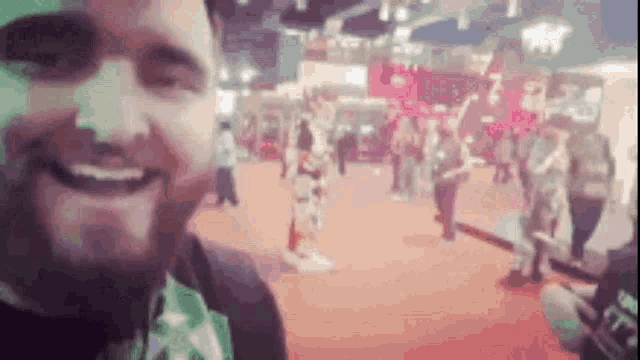 a man with a beard is smiling and taking a selfie in a crowded room .