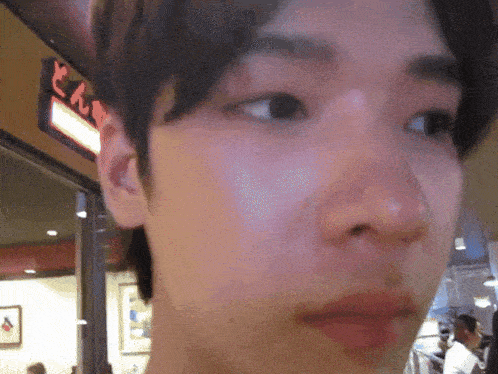 a close up of a man 's face with a sign in the background that says ' n ' on it