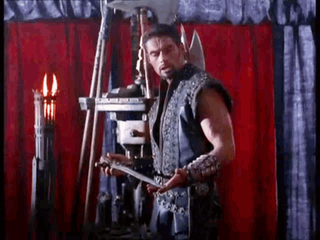 a man is standing in front of a red curtain holding an axe .