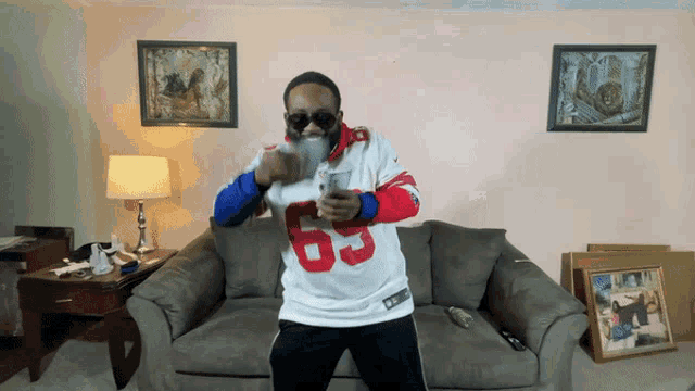 a man wearing a jersey with the number 63 on it is dancing in a living room