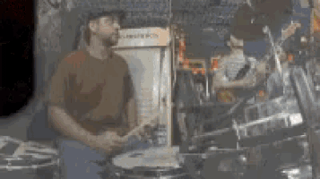 a man in a hat is playing drums in a band .