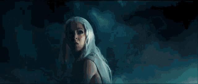 a woman with white hair is smiling while holding a light beam in her hand .