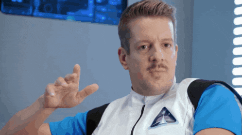 a man with a mustache is wearing a vest with a space ship on it